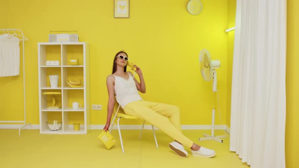 Young Woman Is Talking On Yellow Retro Telephone