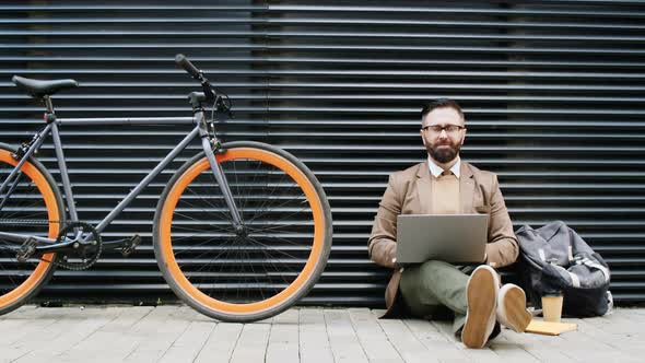 Positive Man with Laptop Posing for Camera on Street