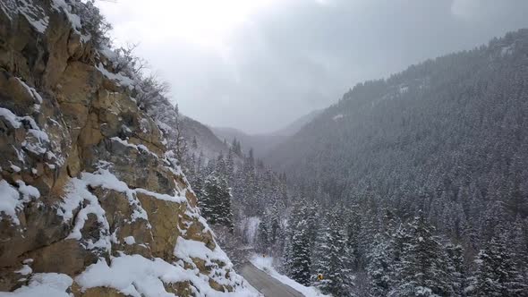 Flying along rocky hill over road during winter