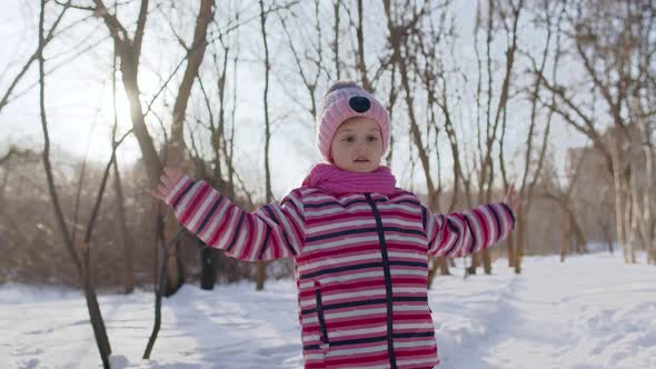 Cheerful Child Girl Kid Walking Smiling Dancing on Snowy Road in Winter Sunny Park Forest Sunset