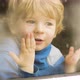 ittle blond boy looking out the window while snowfall outside - VideoHive Item for Sale