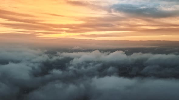 Aerial drone view above the clouds with buildings visible through