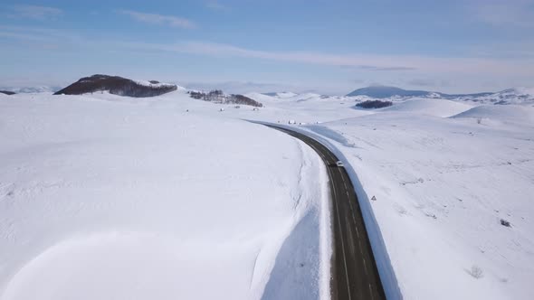 Aerial view of a car on winter road in the forest. Winter landscape countryside in Montenegro