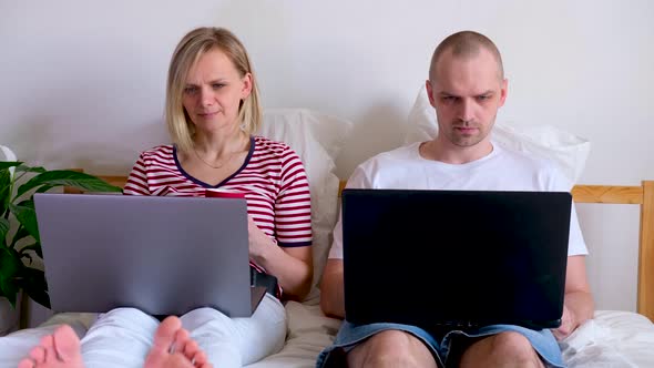 Young Family Works Remotely From Home on Bed at the Computer