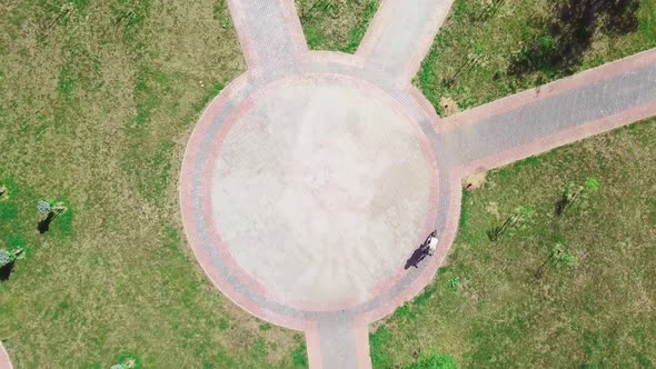 Top view of a bicycle woman riding a bicycle on a circular road in a city park.