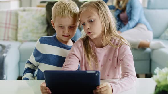 Siblings using a tablet in living room