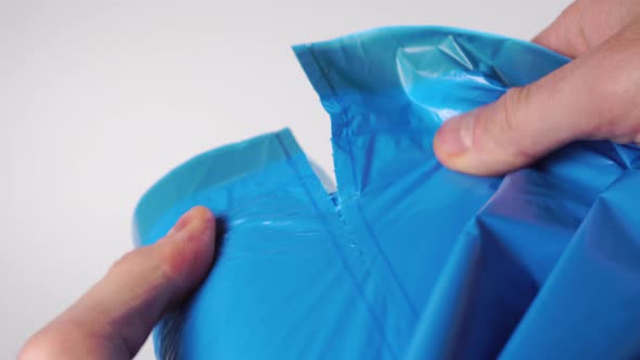 Man tearing off a new blue garbage bag from a roll