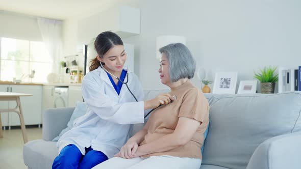 Asian nurse measure heart rate at nursing home take care of disabled senior elderly woman.