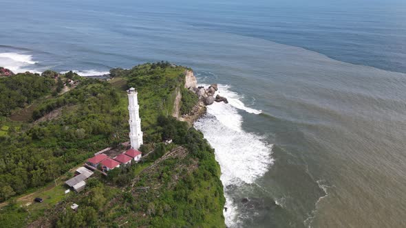 Aerial view of Baron Beach in Gunung Kidul, Indonesia with lighthouse and traditional boat.