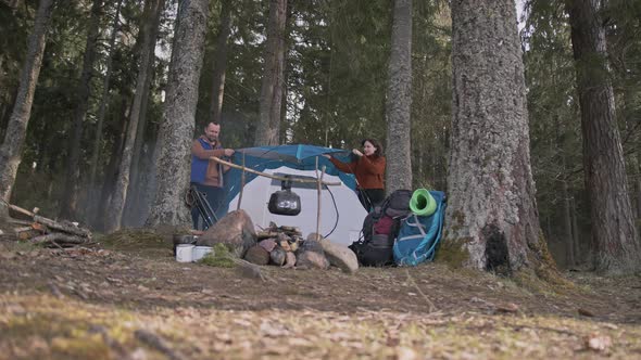 A Couple of Lovers are Setting Up a Tent Throwing a Canopy Over the Tent