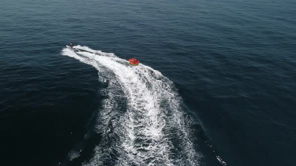 Happy People are Going to Swim on an Air Mattress Behind a Jet Ski