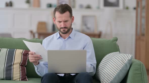 Angry Young Man Working on Documents and Laptop at Home Frustrated