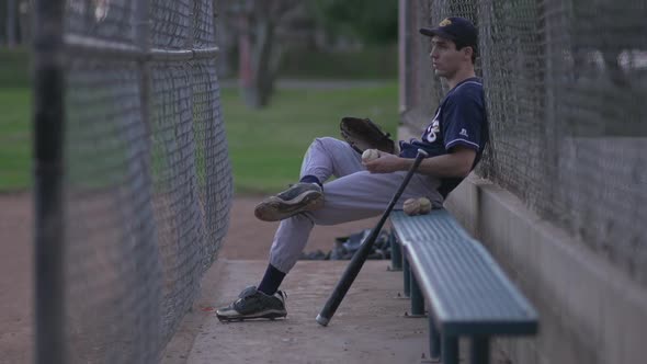 A baseball player resting on the bench.