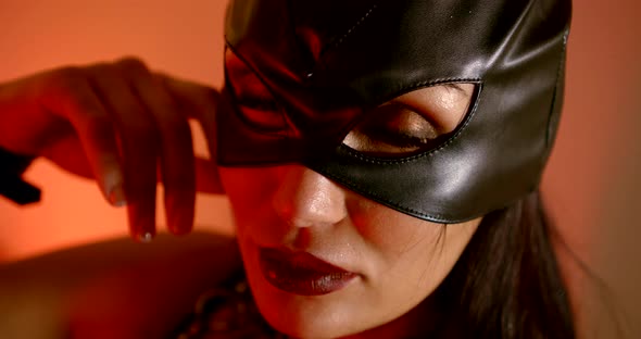 Portrait of a Woman in a Black Leather Mask. Close Up. Red Light