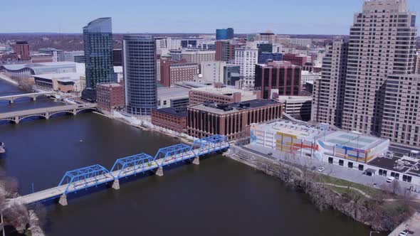 Bridges over still Grand River and Grand Rapids skyline, aerial pan