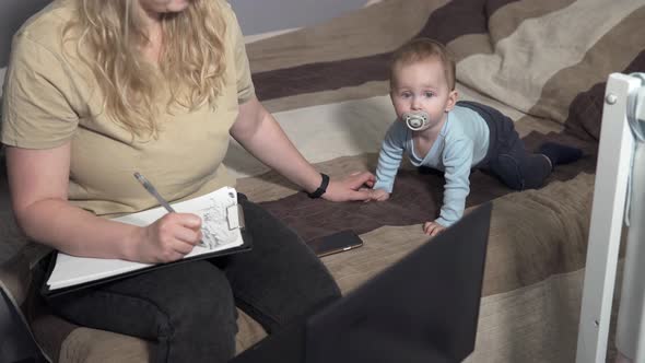 Self-Isolation of Family Life. Mom Works at Home with a Laptop, Distracted by her Child.	