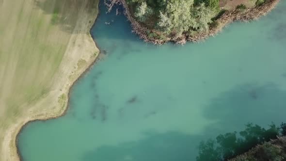 Top down view of golf field pond with light blue water and vivid grass