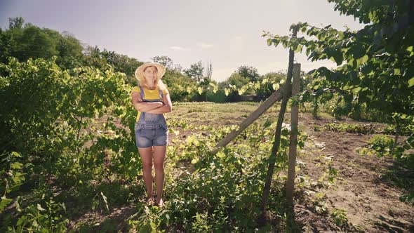 Young woman farmer stands on the plantation. Portrait of a woman gardener in an orchard.
