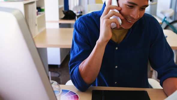 Male executive talking on mobile phone while working at his desk