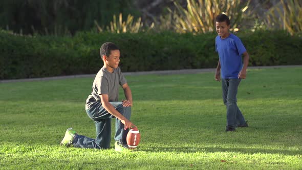 Big brother playing a trick on little brother as he tries to kick a football